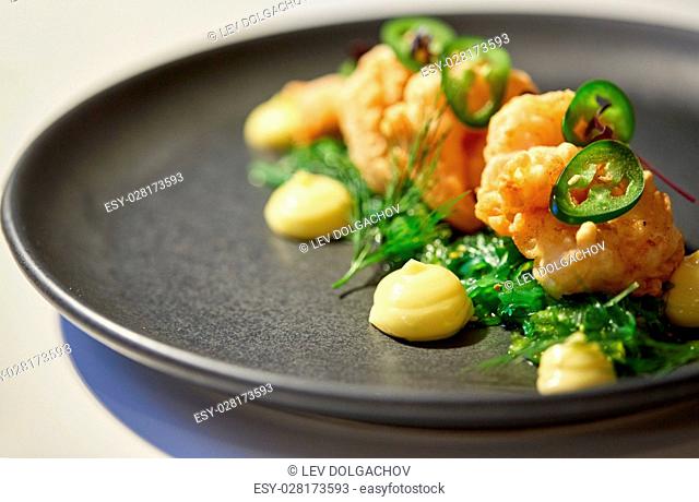 food, new nordic cuisine, culinary and cooking concept - close up of king prawns with jalapeno, wasabi mayonnaise and wakame salad on plate