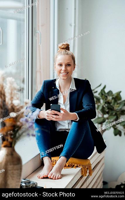Young businesswoman with smart phone sitting at office