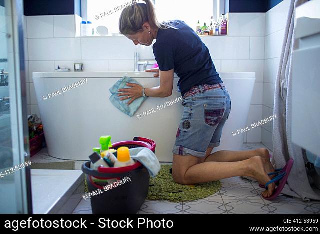 Woman cleaning bathtub in bathroom