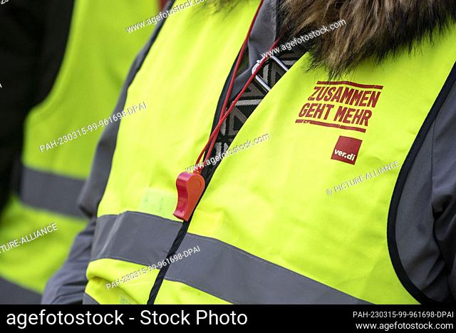 15 March 2023, North Rhine-Westphalia, Gelsenkirchen: Together goes more is written on the strike vest of a woman, in addition she has a whistle hanging around...