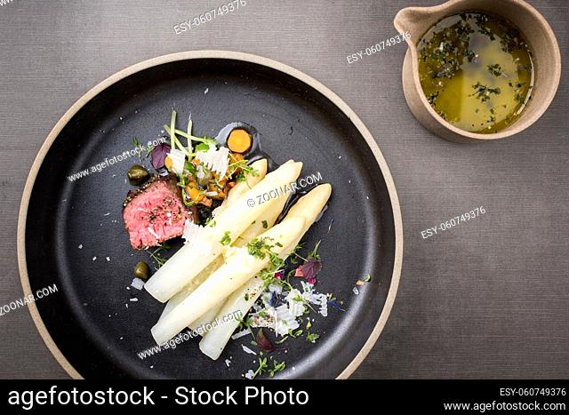 Modern Style classic white asparagus with barbecue dry aged sliced beef fillet and vegetable served as top view on a minimalistic design plate