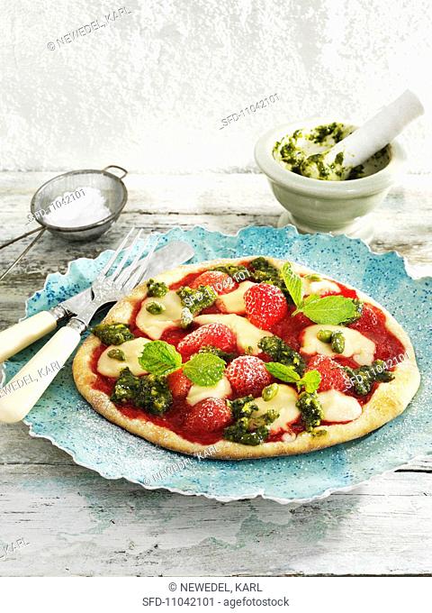 A sweet pizza topped with strawberries, marzipan and pistachio pesto