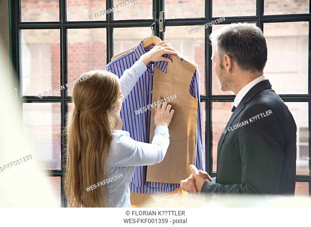 Young seamstress showing customer tailor made shirt