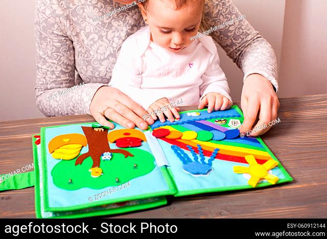 The woman and cute little girl play with an interesting soft book