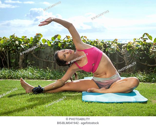 Amputado de raza mixta practicando yoga en el césped