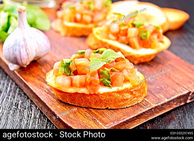 Bruschetta with tomato, basil and spinach on a plate, vegetable oil in a decanter on wooden board background