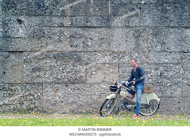 Photographer standing in front of a wall with his motor scooter
