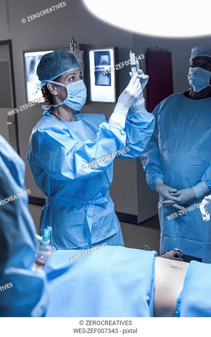 Doctor preparing syringe for patient in operating room