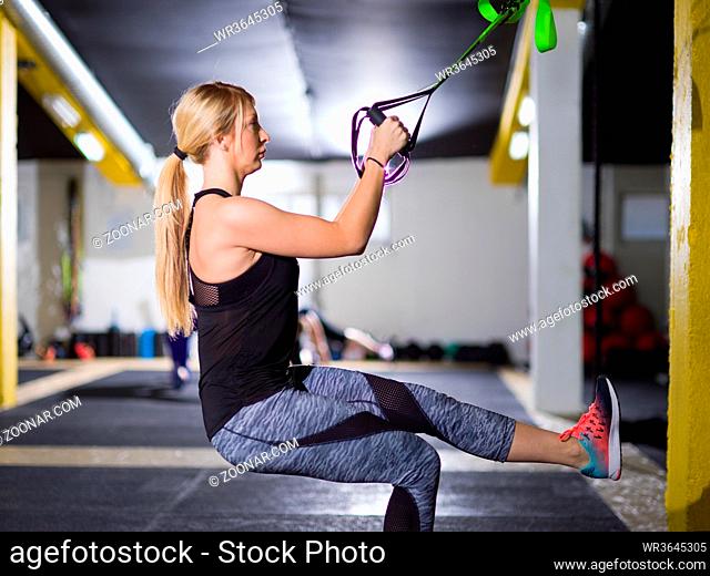 young athlete woman working out pull ups with gymnastic rings at the crossfitness gym