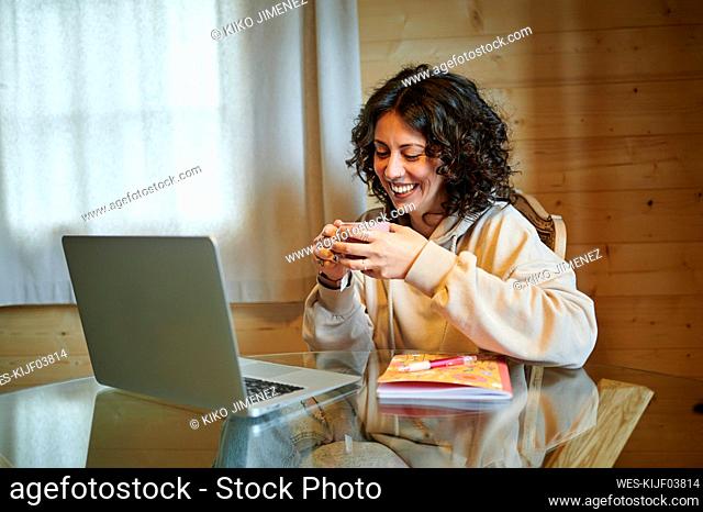 Happy woman having tea in front of laptop at home