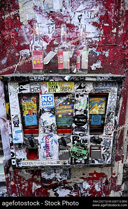 PRODUCTION - 15 July 2023, Berlin: A chewing gum vending machine hangs on the facade of a building next to a store on Oranienstrasse in Kreuzberg and is also...