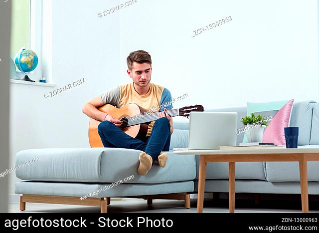 Handsome young man playing acoustic guitar