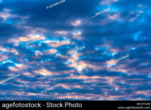 Beautiful clouds in blue sky, illuminated by rays of sun at colorful sunset to change weather. Soft focus, motion blur abstract summer meteorology landscape