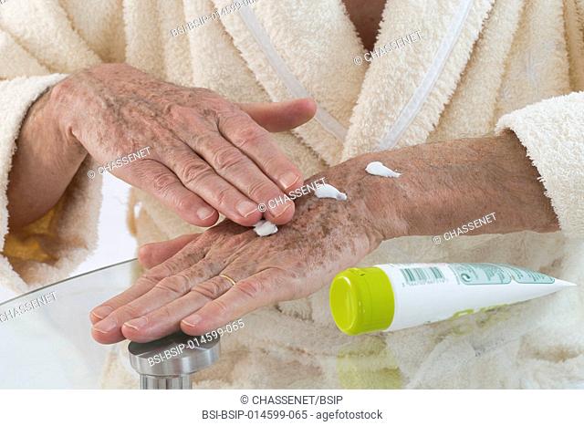 Senior man applying cream on his hands