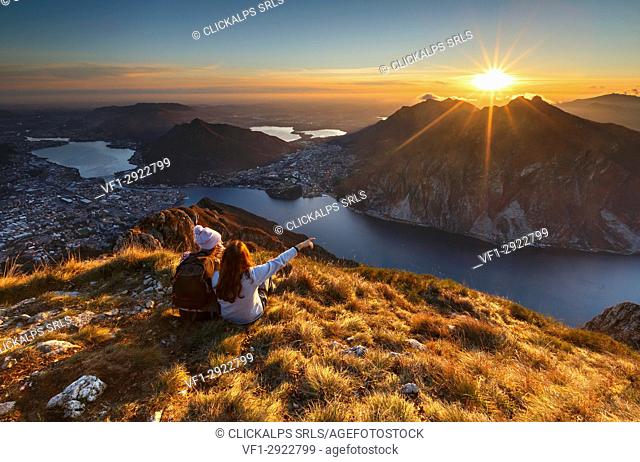 Lake Como, Lombardy, Italy. Two friends watching a scenic sunset from above Lecco city