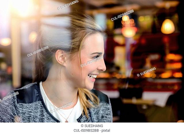 Young woman in cafe window seat, view through window