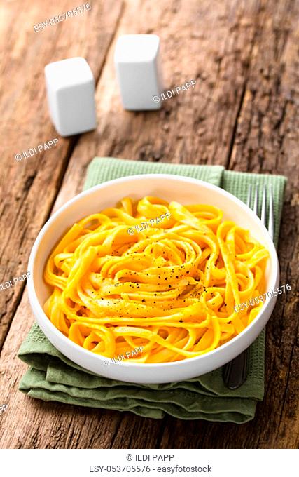 Fettuccine pasta with fresh homemade creamy pumpkin alfredo sauce garnished with freshly ground black pepper and served in bowl