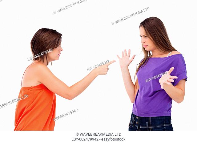 Teenage girl accusing her friend by pointing at her with her finger