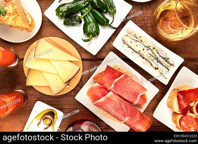 Spanish tapas and wine, the cuisine of Spain shot from the top on a dark rustic wooden background