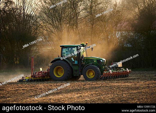 tractor with harrow on a field, agriculture, sunset, bavaria, germany