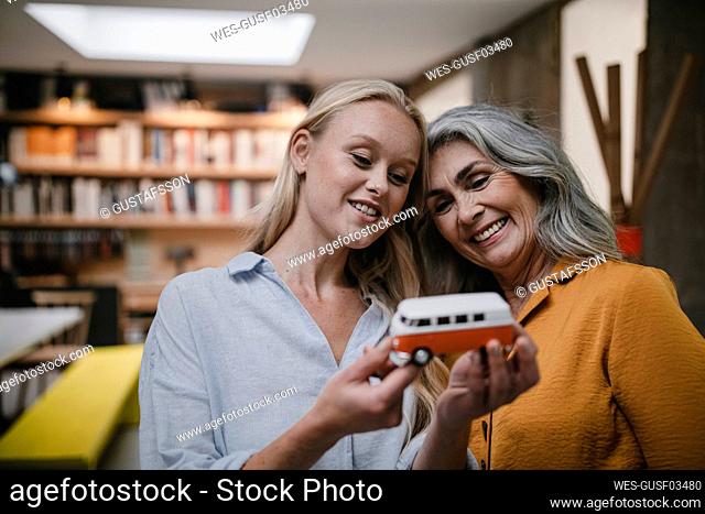 Portait of happy mother and adult daughter holding van model