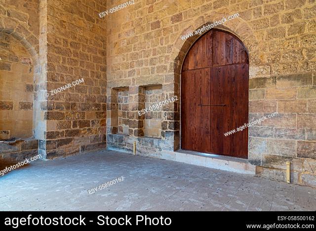 Arched wooden door and two embedded niches in stone bricks wall, at the public Mosque attached to Al-Muayyedi Bimaristan historic building