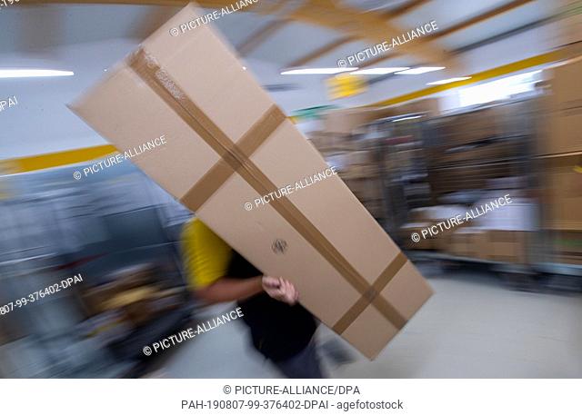 07 August 2019, Mecklenburg-Western Pomerania, Wittenburg: Parcel carrier Sabine Weiß sorts parcels for her tour at Deutsche Post's delivery base