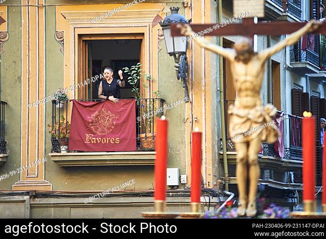 dpatop - 05 April 2023, Spain, Granada: A woman raises her arm and with powerful gestures sings a ""saeta"" from a balcony to the Cristo del Consuelo (Christ of...