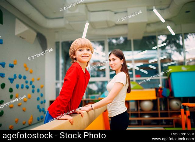 Kids doing balance beam gymnastics exercises in gym at kindergarten or elementary school. Children sport and fitness concept