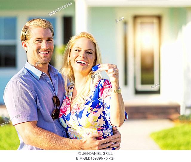 Caucasian couple holding keys outside new home