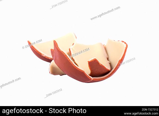 Close up front view of milky and white chocolate egg broken into pieces, isolated on white background