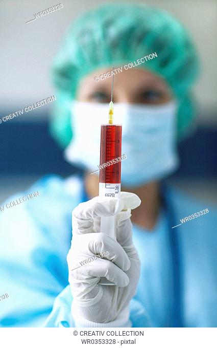 Surgeon holding syringe in foreground