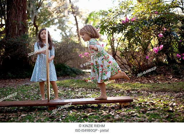 Girl holding plastic hoops with sister running through