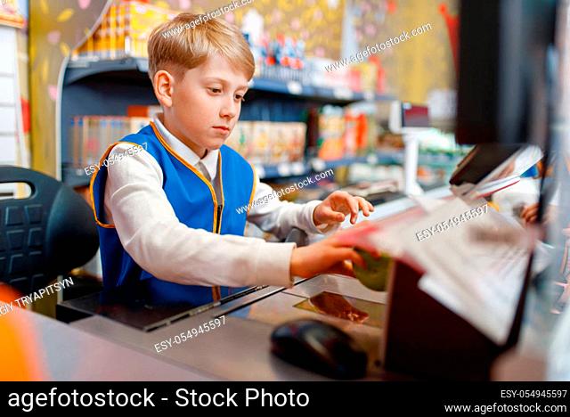 Little boy in uniform at the register playing salesman, playroom. Kids plays sellers in imaginary supermarket, sales profession learning