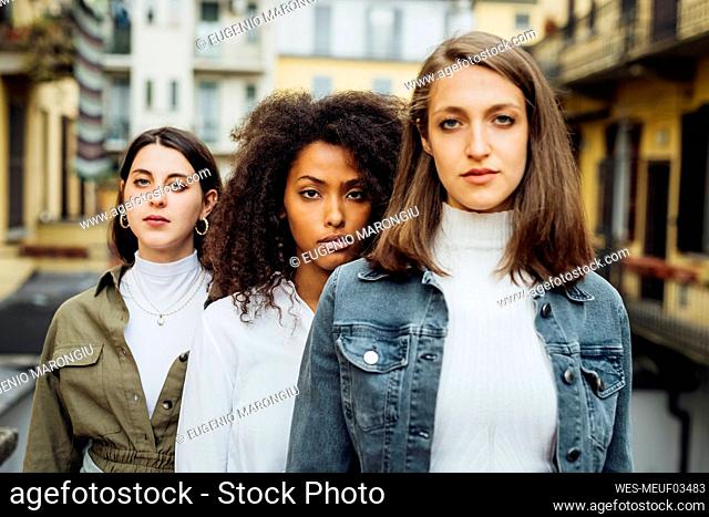 Women staring while standing behind friend at terrace