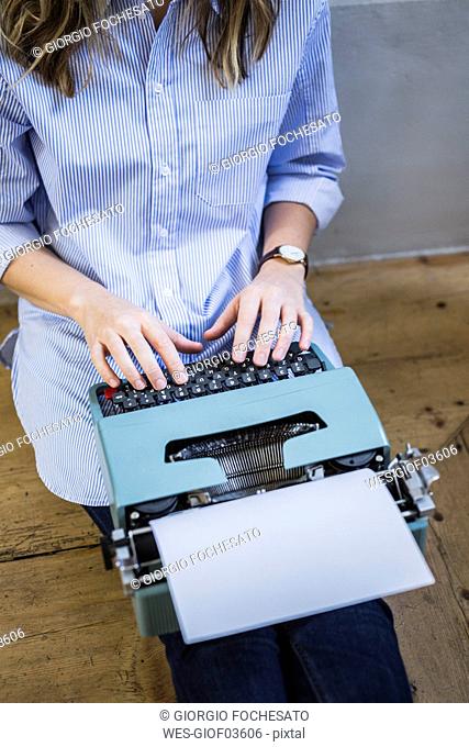 Close-up of woman sitting on the floor using typewriter