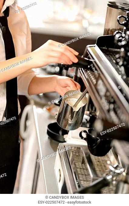 Barista steaming milk for hot cappuccino