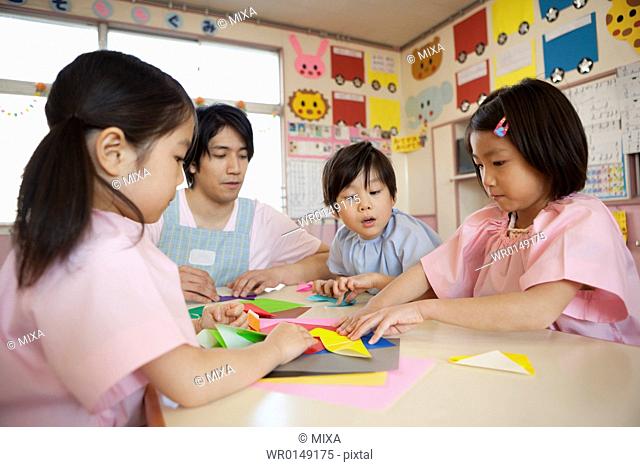 Kindergarten Teacher and Children Playing Origami