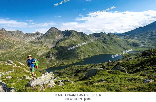 Hiker on a stone, view into the valley on the Giglachsee lakes, Schladminger Höhenweg, Schladminger Tauern, Schladming, Styria, Austria