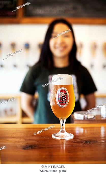 Beer glass standing on a counter, woman in the background