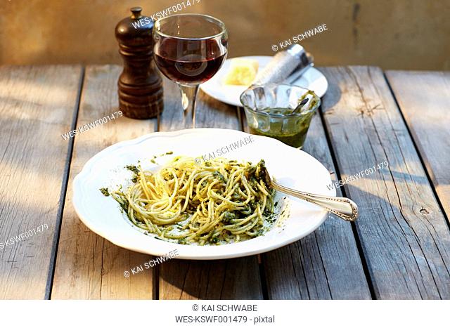 Dish of spaghetti with basil pesto and glass of red wine