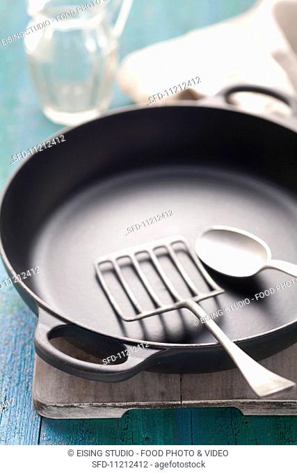 An empty, black frying pan with a frying spatula and a tablespoon