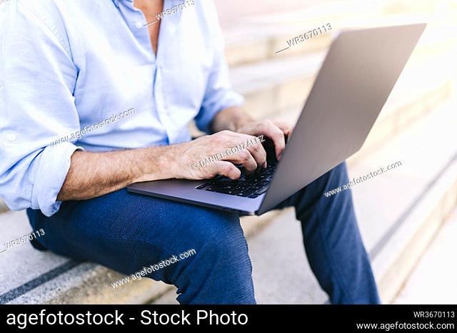 Businessman working on laptop while sitting on steps