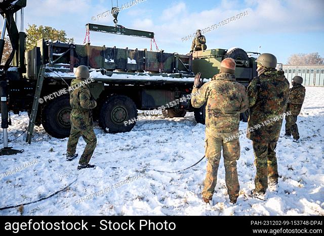 PRODUCTION - 01 December 2023, NA: Participants and a Bundeswehr instructor (M) stand in front of a truck with containers for a Patriot launcher during a...