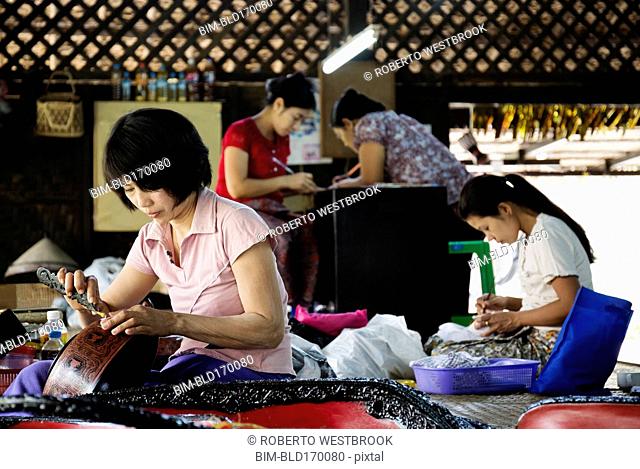 Asian artisans carving traditional designs in workshop