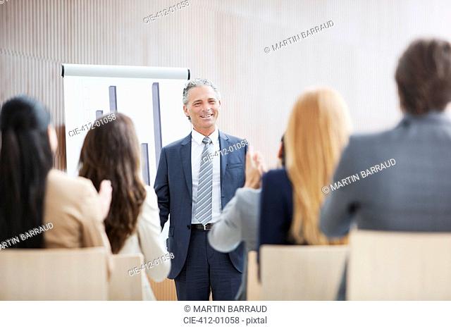 Business people applauding businessman standing at flipchart
