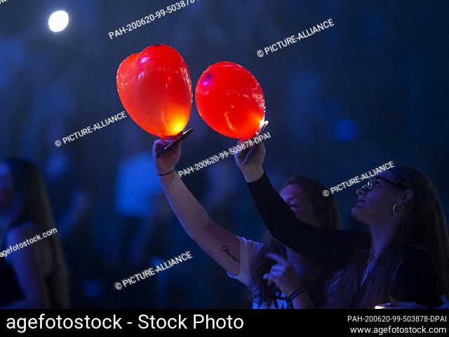 20 June 2020, North Rhine-Westphalia, Cologne: Female fans of singer Wincent Weiss light up red balloons. Weiss appeared again at an arena concert after a...