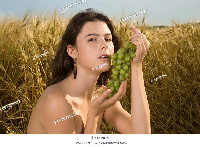Beautiful slavonic girl on picnic in wheat field with grapes