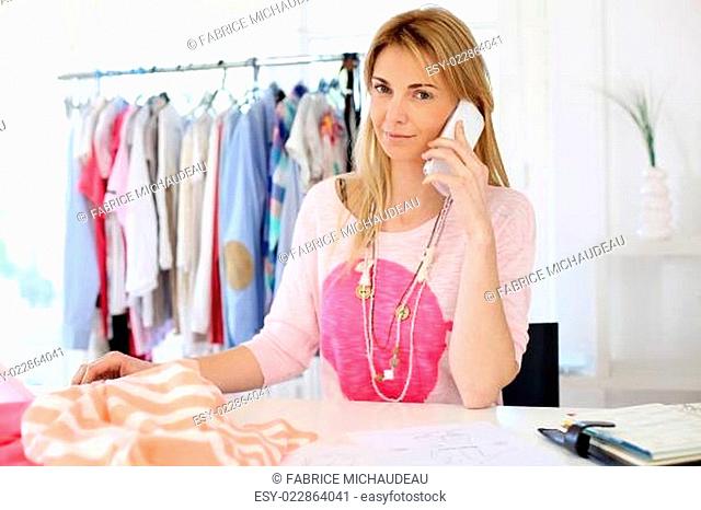 Woman designer in workshop talking on the phone
