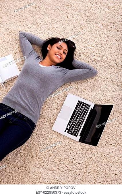 Young Woman Lying On Carpet With Laptop
